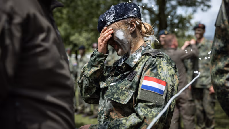 Een vrouwelijke militair met bier op haar schouders, gezicht en baret.