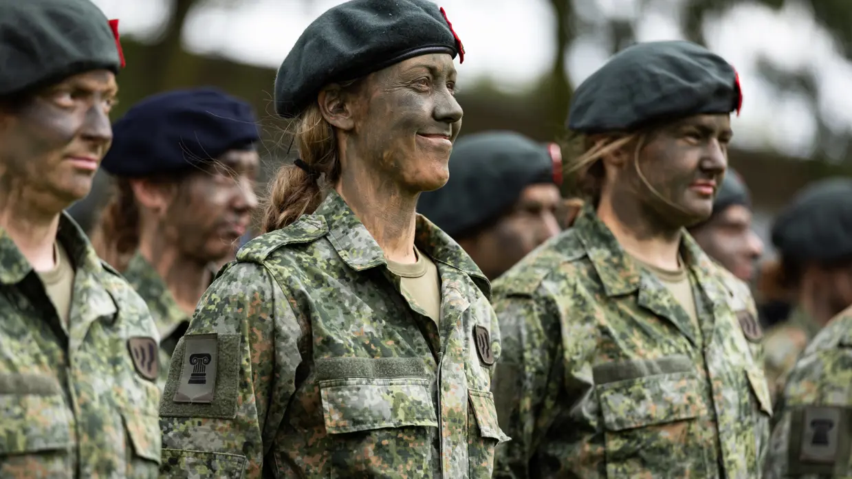 Militairen met baretten staan opgesteld. 