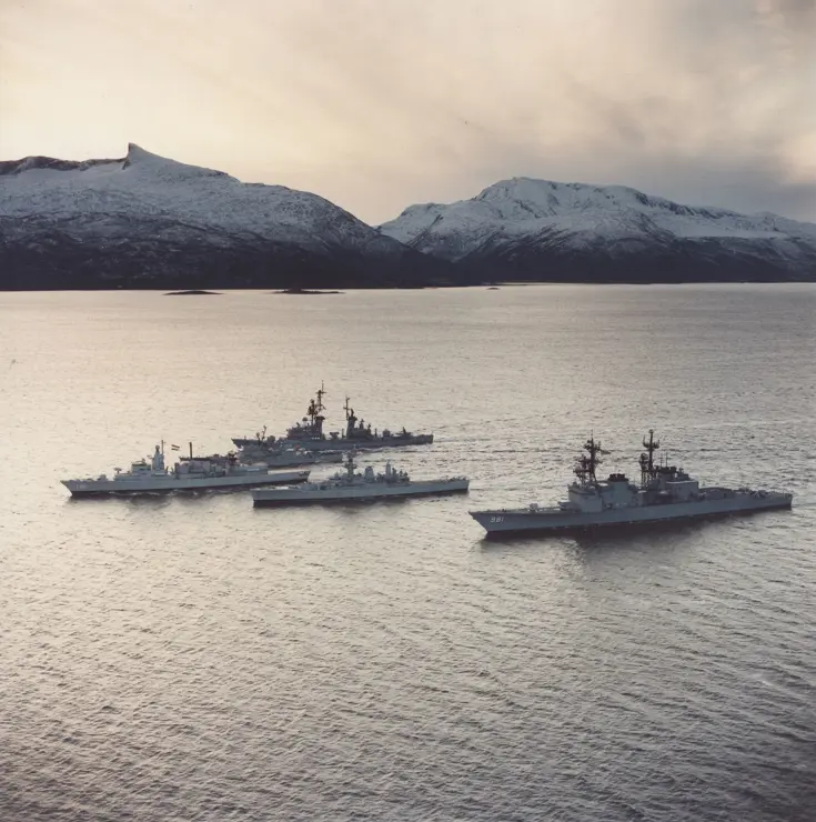 Foto uit 1986. Fregat Hr. Ms. Witte de With als eenheid van de Stanavforlant (Standing Naval Force Atlantic) op zee voor besneeuwde bergen.