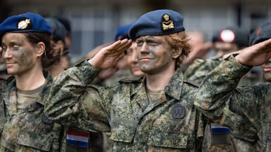 Militairen met baretten staan opgesteld. 