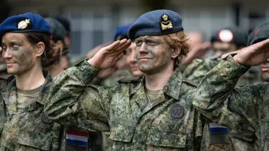 Militairen met baretten staan opgesteld. 