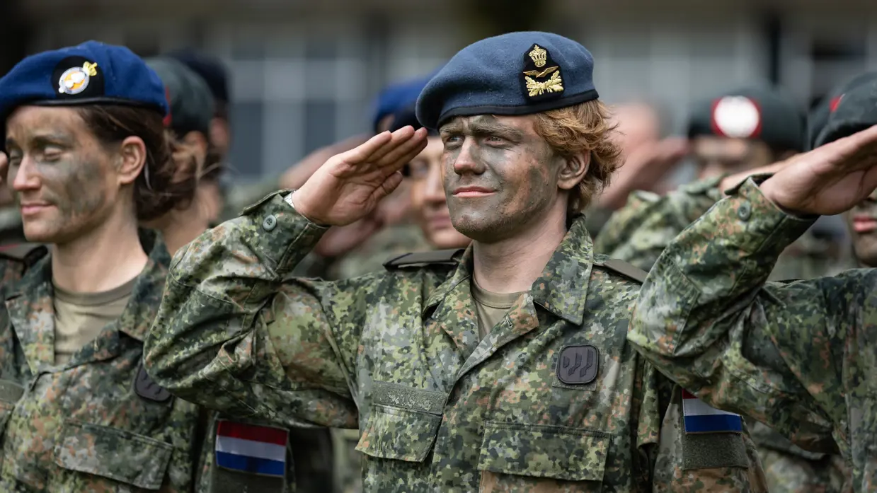 Militairen met baretten staan opgesteld. 