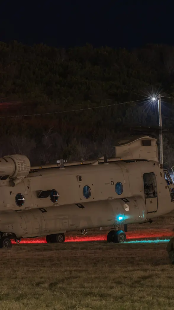 Nachtopname van een Chinook op de grond met luchtmobiele infanteristen er omheen.