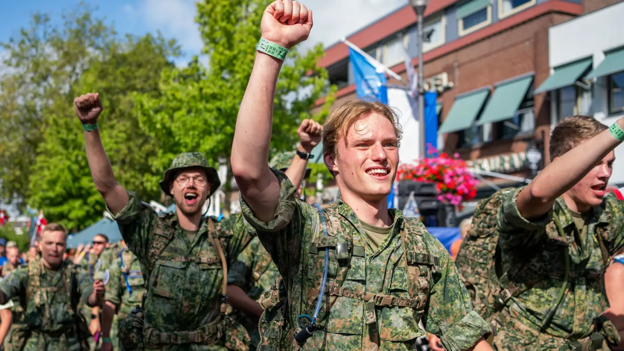 Wandelende militairen lachen en juichen door de straten van Elst.  