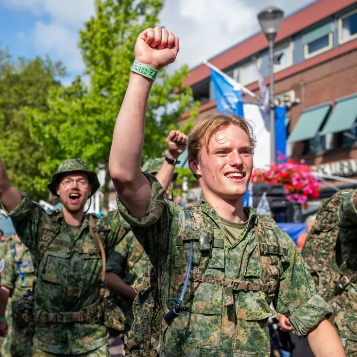Wandelende militairen lachen en juichen door de straten van Elst.  