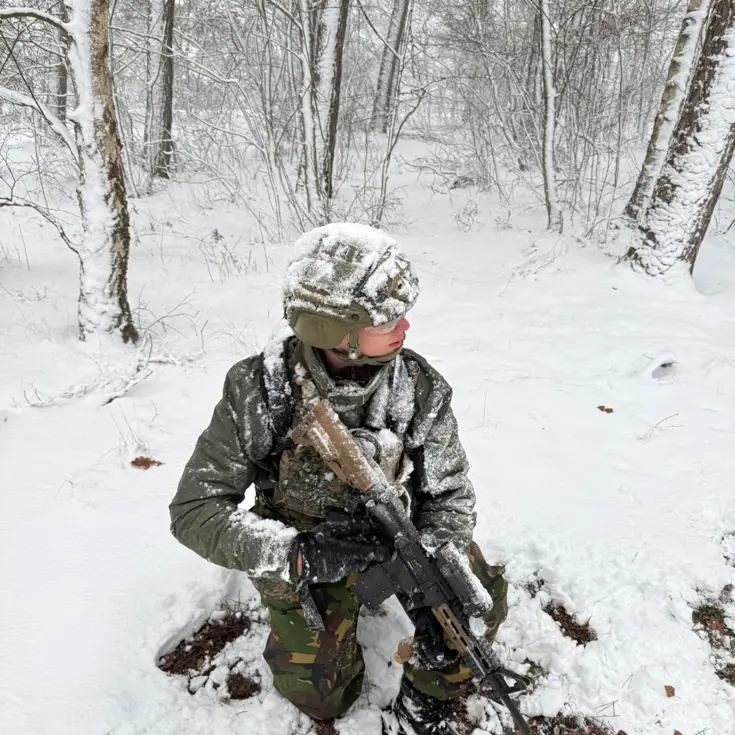 Marechaussee met lang wapen in de sneeuw.