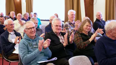 Heren en dames applaudiseren in een zaal.