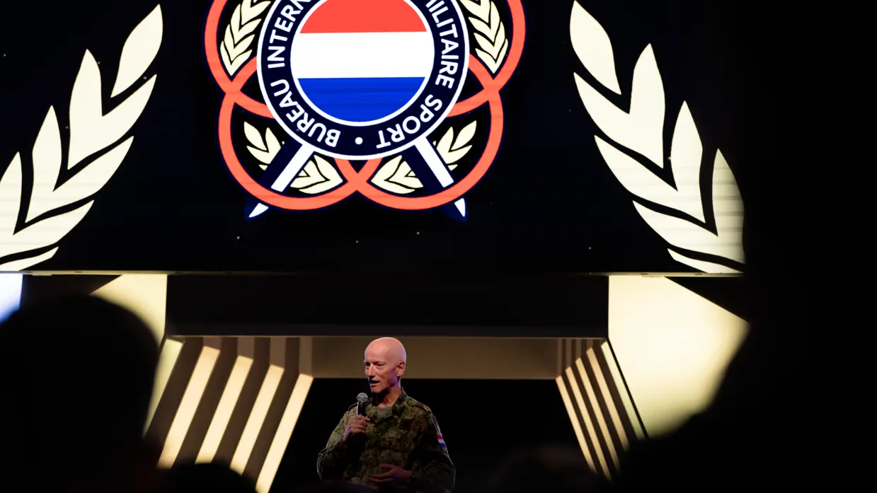 Brigadegeneraal Laurens Jobse achter een spreekgestoelte met een spandoek op de achtergrond.