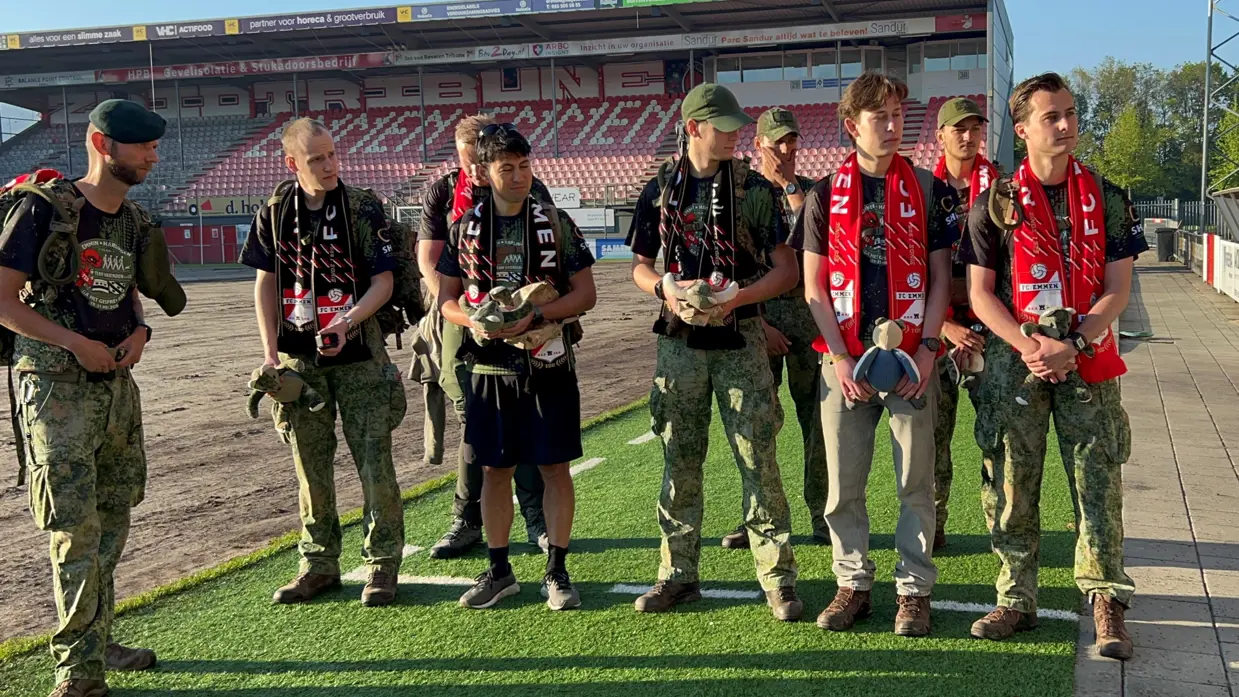 De militairen staan bij een voetbalclub. 