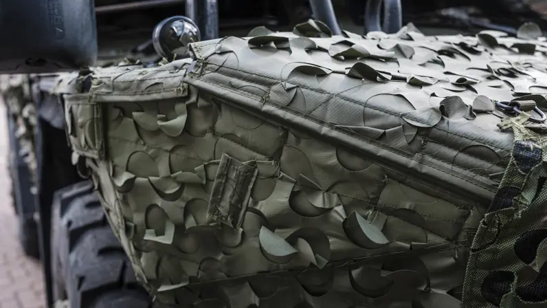 Een militair voertuig met daarop een camouflagesysteem.
