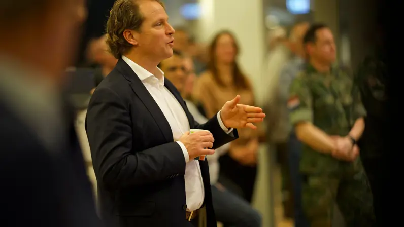 Staatssecretaris Gijs Tuinman spreekt een groep mensen toe en gebruikt daarbij zijn handen.