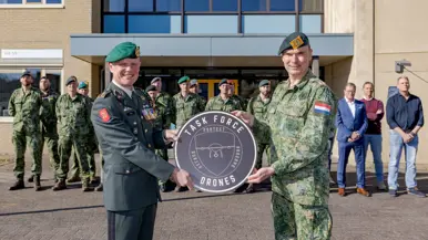 Logo Task Force Drones wordt onthuld en borden met protect, observe en attack; hun motto.