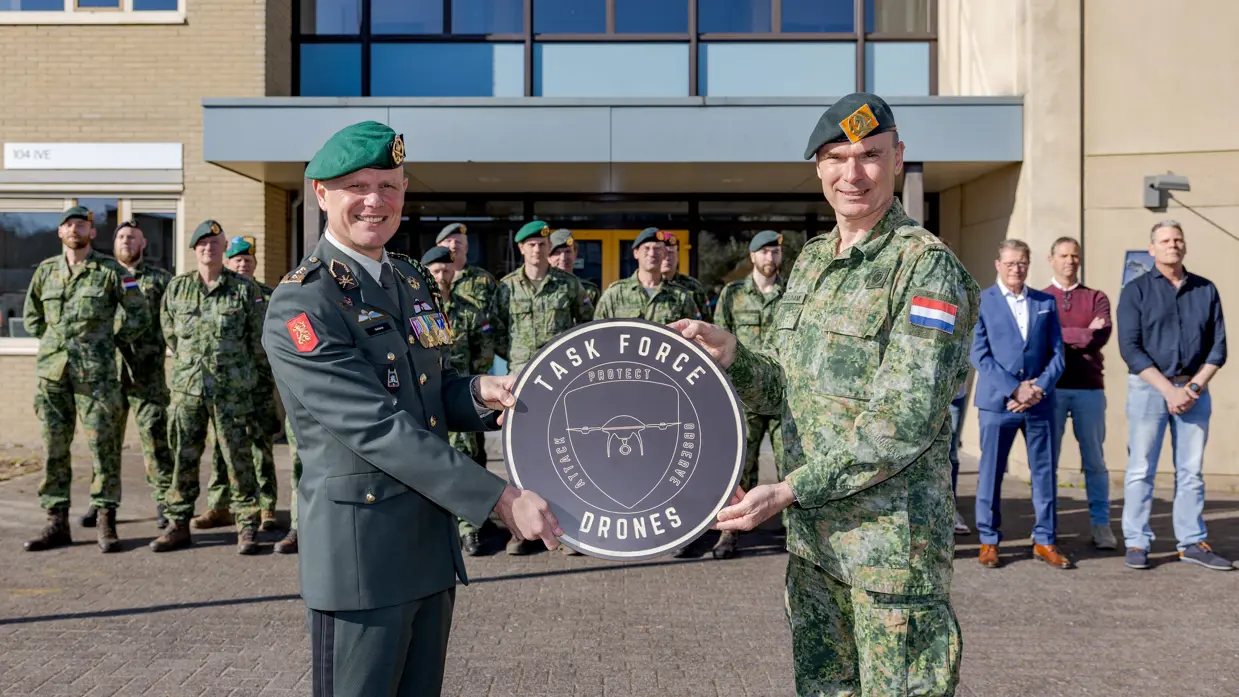 Logo Task Force Drones wordt onthuld en borden met protect, observe en attack; hun motto.
