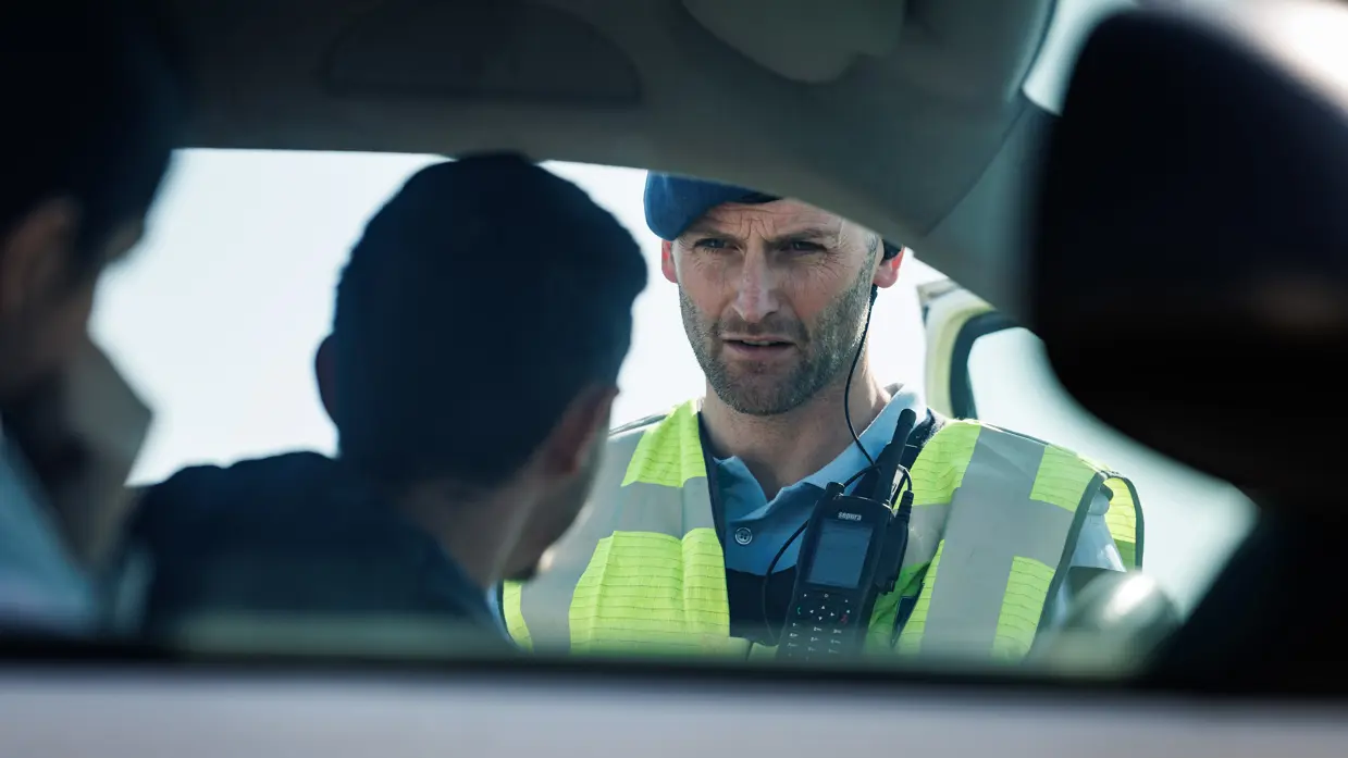  Een marechaussee praat door het raam van een auto met een bestuurder.