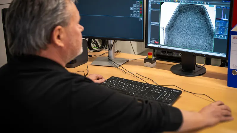 Een medewerker van de veldmaskerwerkplaats keurt de scan van een ballistische plaat op een computerscherm