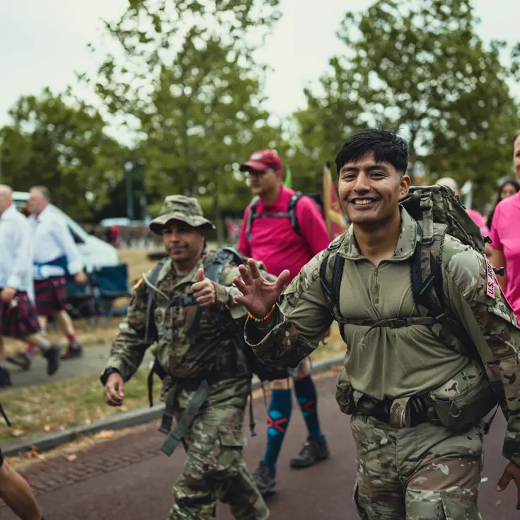  Een Amerikaanse militair zwaait en kijkt in de camera, omringd door andere lopers.
