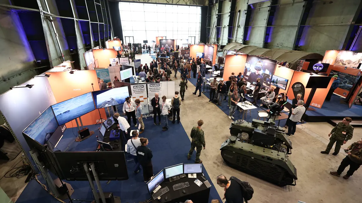 De zaal vanaf bovenaf gezien met daarin verschillende stands.