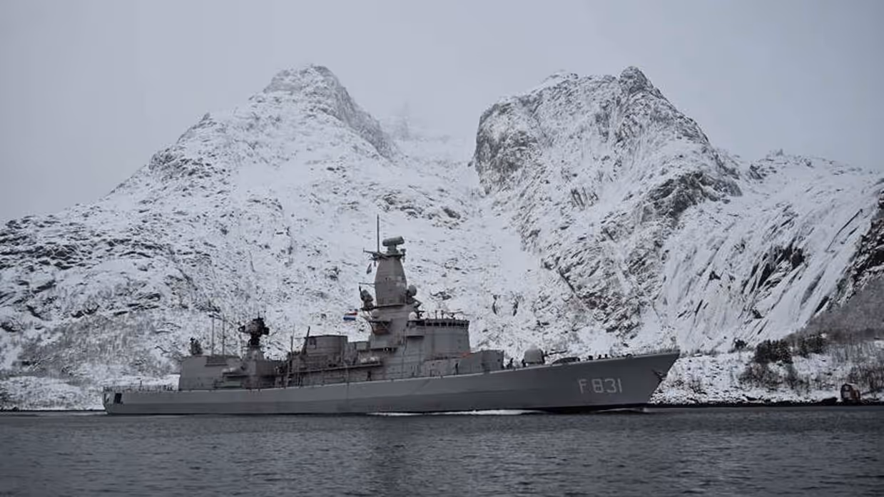 De Zr.Ms. Van Amstel vaart voor besneeuwde rotsen langs.