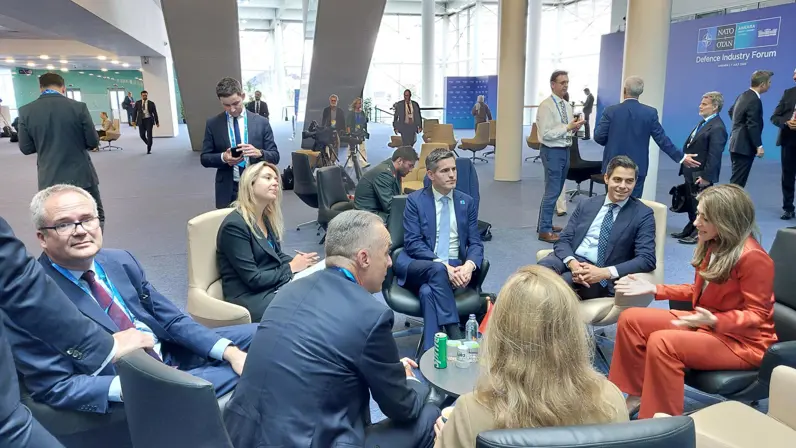 Groepje mensen zit op stoelen in een kring tijdens overleg in conferentieruimte.
