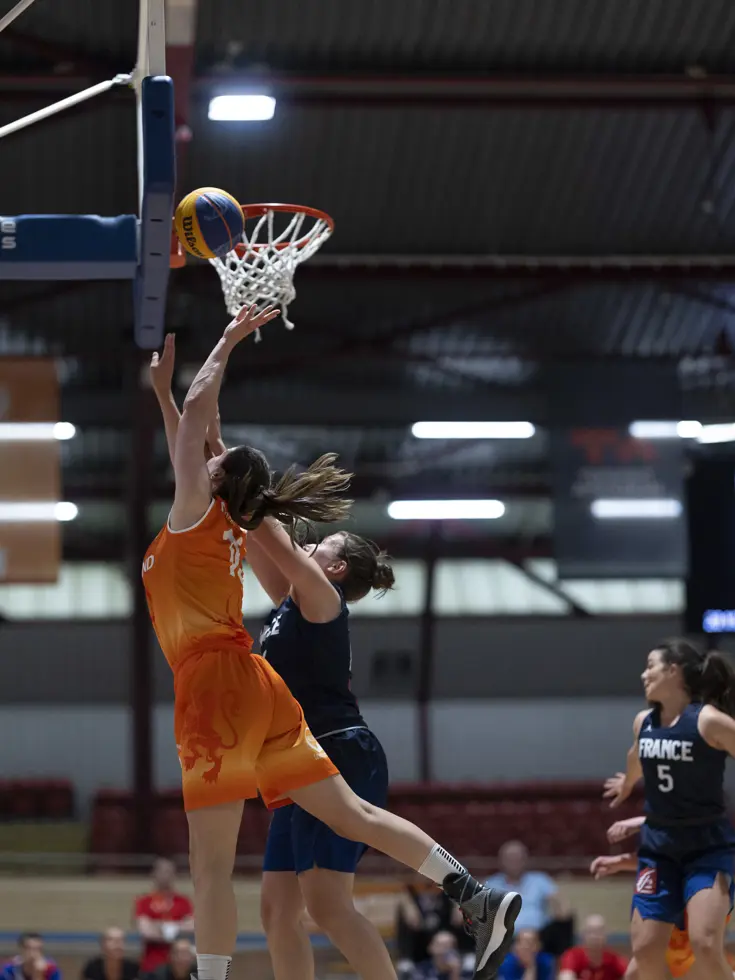 Een basketballer onder de basket in een sportzaal.