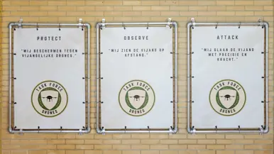 Logo Task Force Drones wordt onthuld en borden met protect, observe en attack; hun motto.