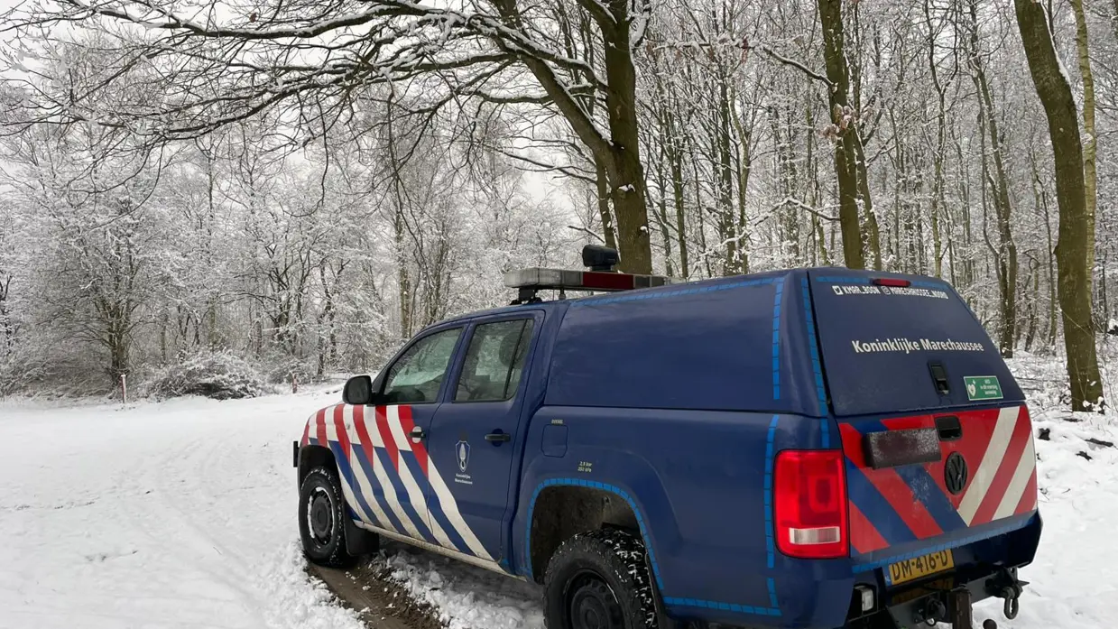 Voertuig van de Marechaussee in een besneeuwd bos.