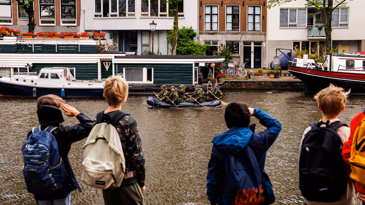 De deelnemers aan de NWT roeien in rubberboten door Amsterdam.