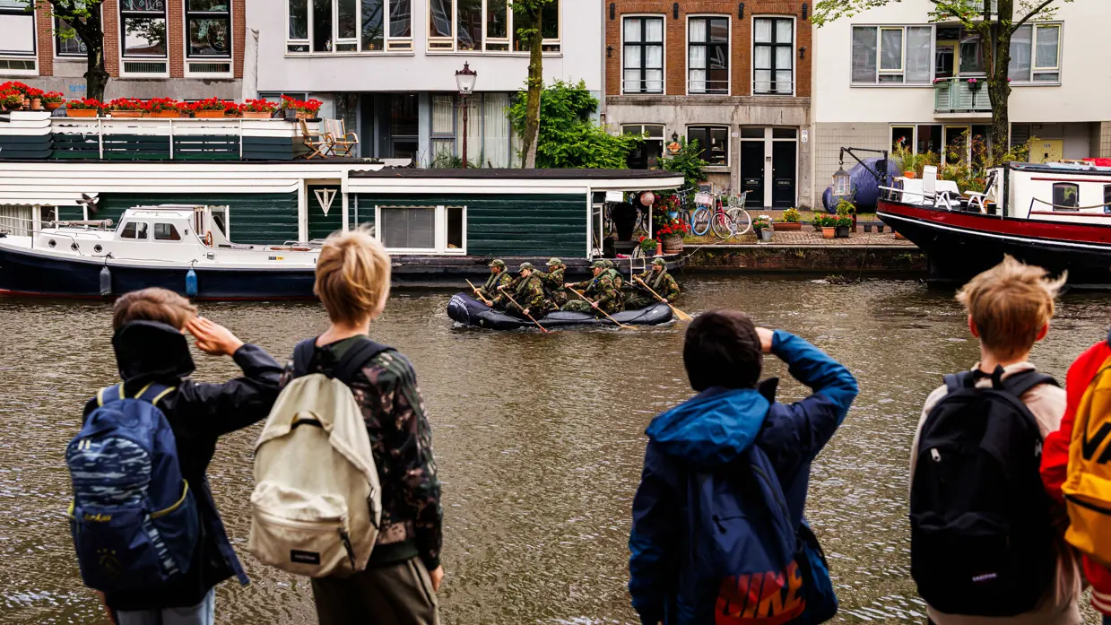 De deelnemers aan de NWT roeien in rubberboten door Amsterdam.