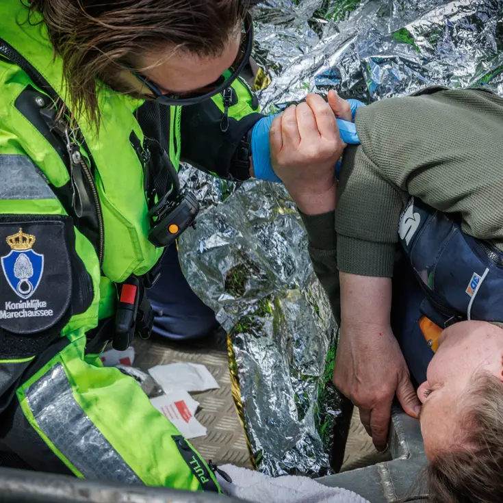 Marechaussee houdt de hand vast van een lotusslachtoffer. 