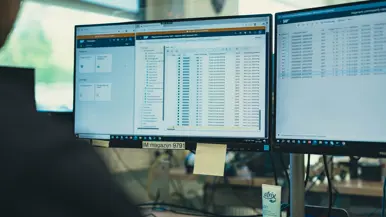 Twee computerschermen met daarop het nieuwe systeem.