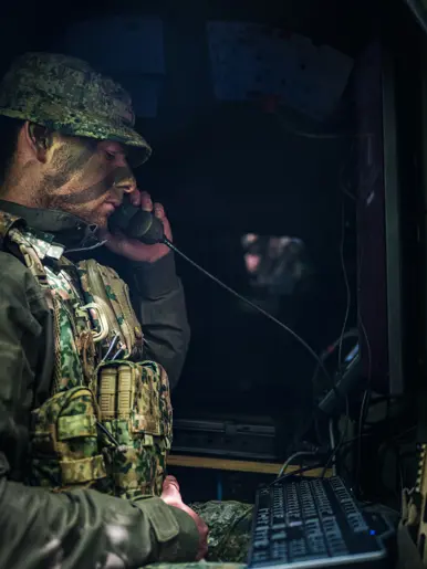 Een bellende militair in een donkere ruimte.