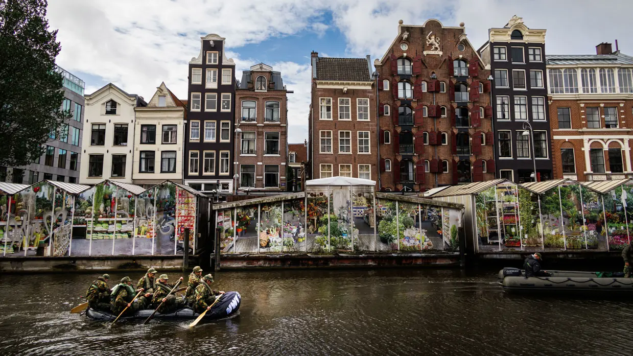 De deelnemers aan de NWT roeien in rubberboten door Amsterdam.