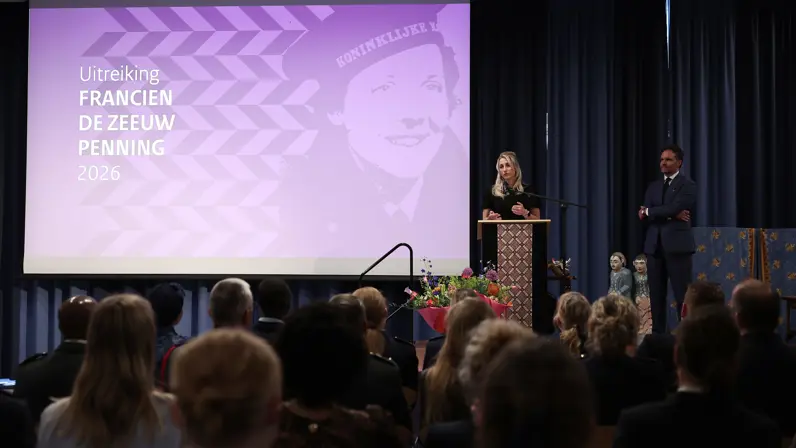 Amber spreekt door de microfoon, gezien vanuit de gevulde zaal.
