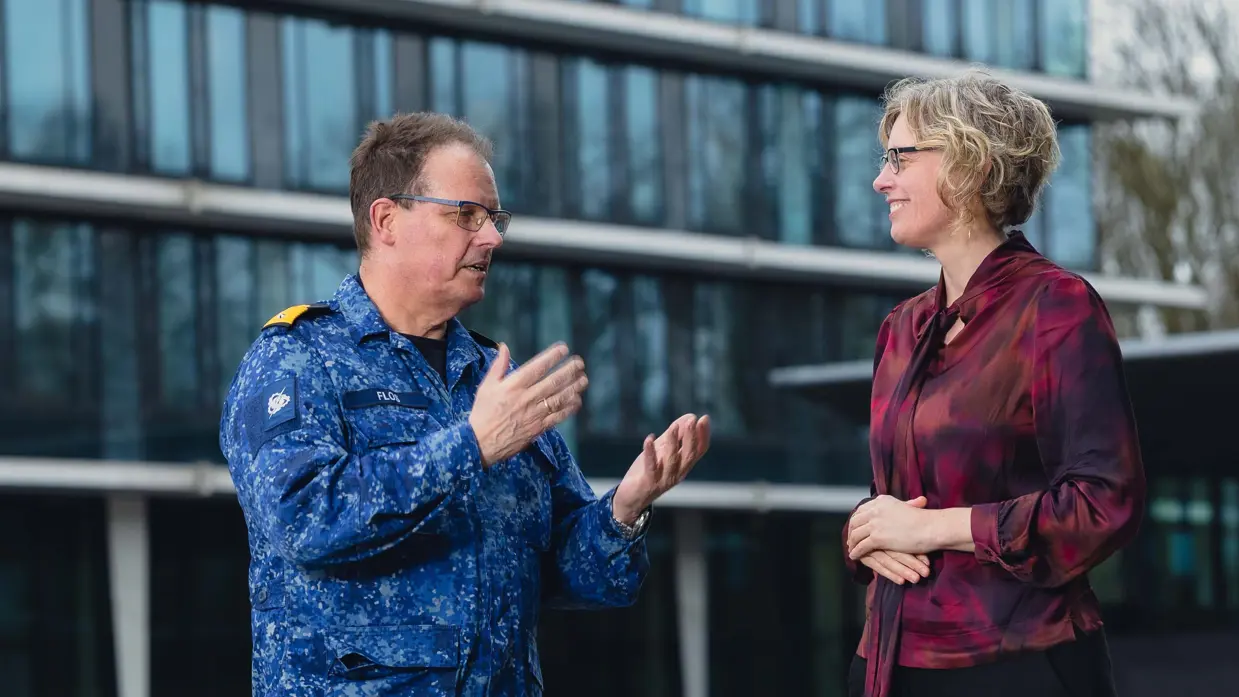Commandeur Flos in blauw gevechtspak in gesprek met Carine van Bentum. 