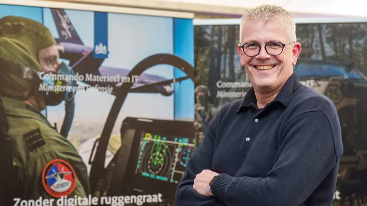Man met armen over elkaar kijkt lachend in de camera.