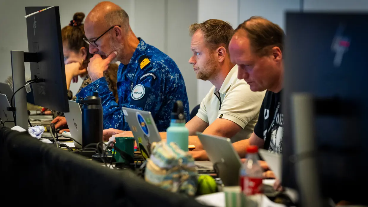 Burgermedewerkers en een marineman werken achter hun eigen beeldscherm.