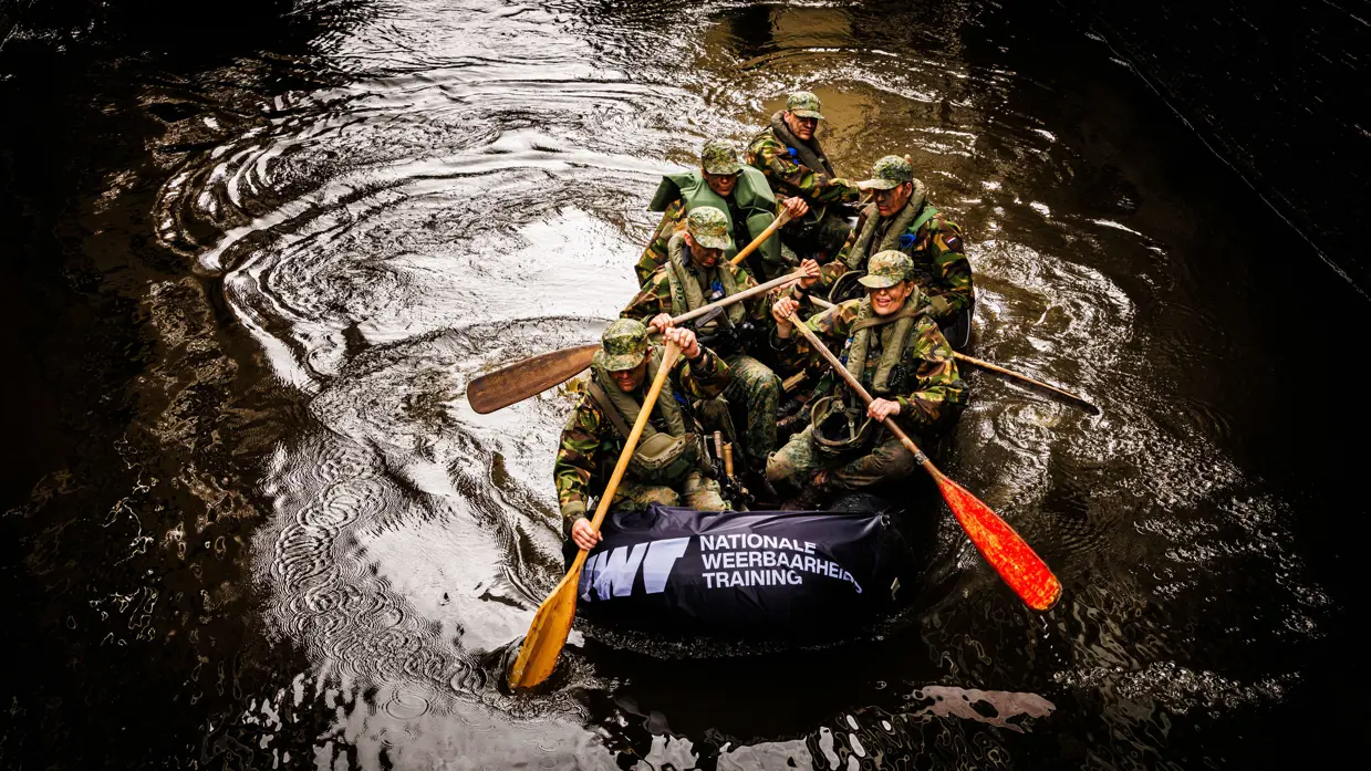 De deelnemers aan de NWT roeien in rubberboten door Amsterdam.