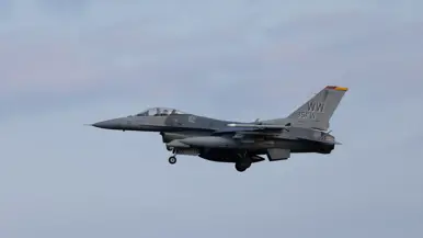 Een F-16 in de landing onder een blauwe lucht. 