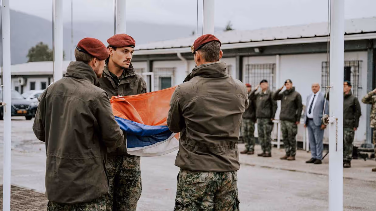 3 militairen vouwen de Nederlandse vlag op.