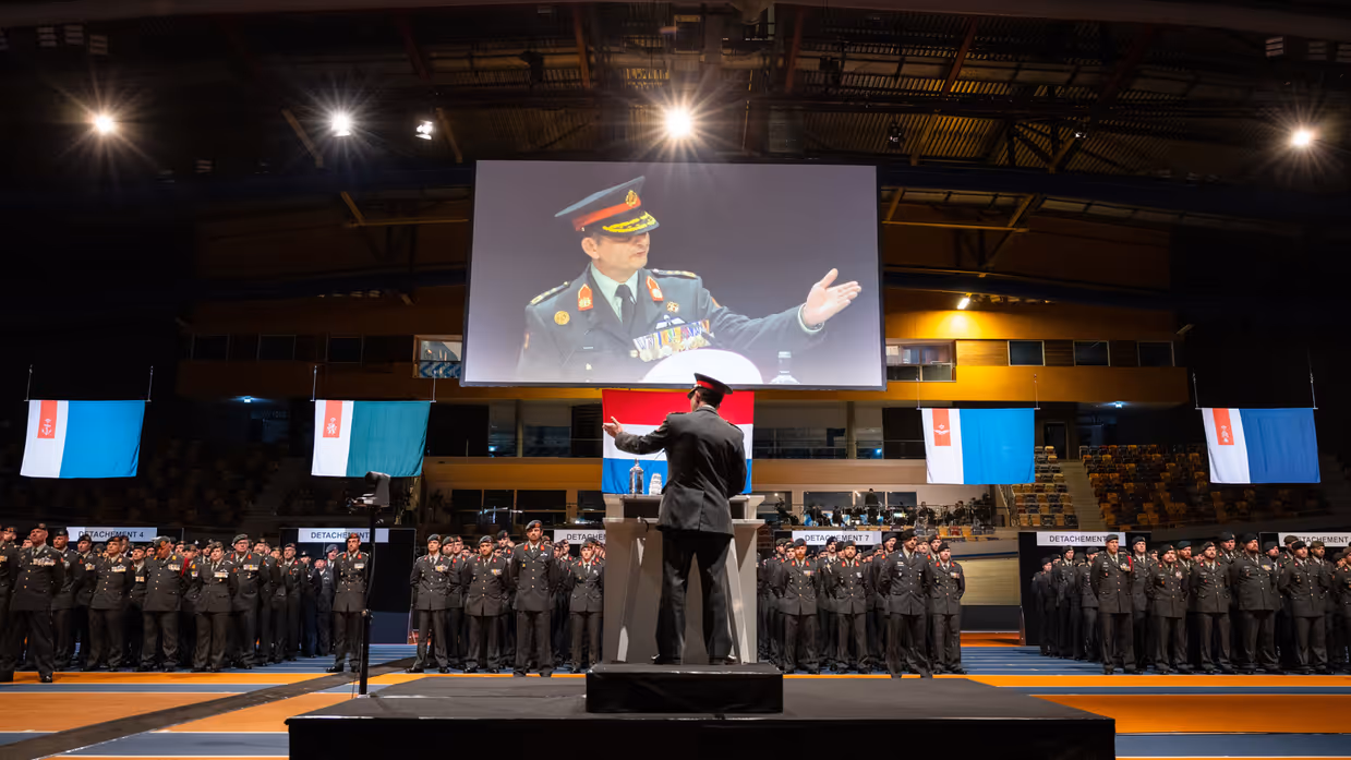 Militair geeft toespraak aan volle zaal met militairen.