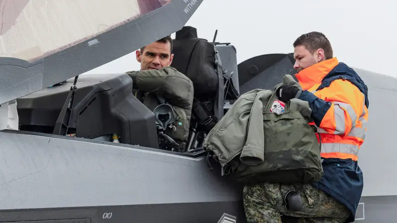  Een man zit in de cockpit van een F-35, een man aan de zijkant van het vliegtuig spreekt tegen hem.