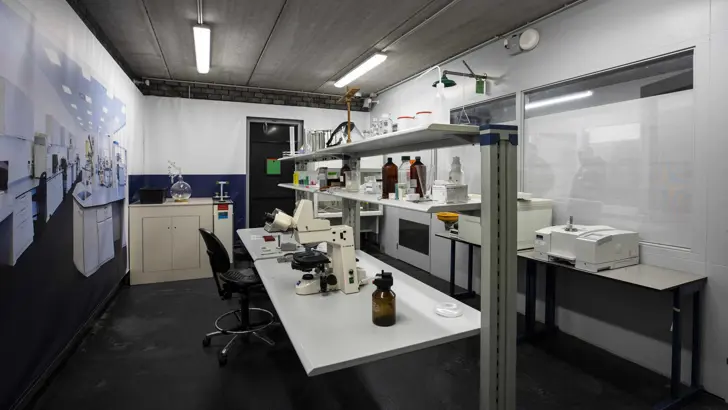 Bureau met flesjes en microscoop.