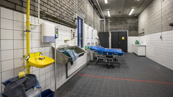 Ontsmettingsruimte met bedden, wasbak en douches.