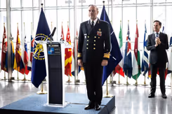 Rob Bauer in de houding naast een katheder met NAVO-logo erop. Op de achtergrond secretaris-generaal Mark Rutte.