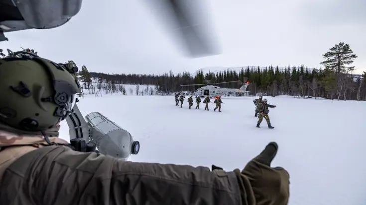 Militairen stappen uit helikopter in sneeuwlandschap.