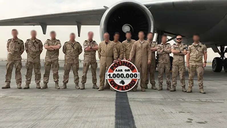 Groep militairen staat voor een KDC-10-vliegtuig tijdens een buitenlandse inzet. 