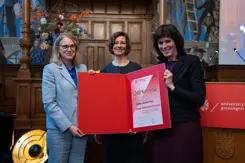 3 vrouwen houden een oorkonde vast.