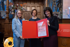 3 vrouwen houden een oorkonde vast.