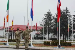 2 Nederlandse militairen salueren voor een rij vlaggen.