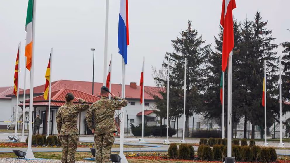 2 Nederlandse militairen salueren voor een rij vlaggen.
